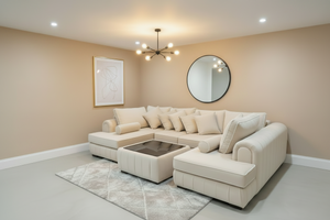 Beige sectional sofa in a living room with a round mirror and framed artwork on the wall.