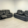 Gray reclining sofa set in a room with white walls and floor.